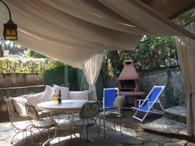 patio con mesa, sillas y fogones en Bougainvillea 3+3, en Marina di Castagneto Carducci