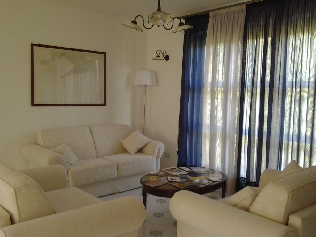 a living room with white furniture and a chandelier at Affittacamere Aria in Sessa Cilento