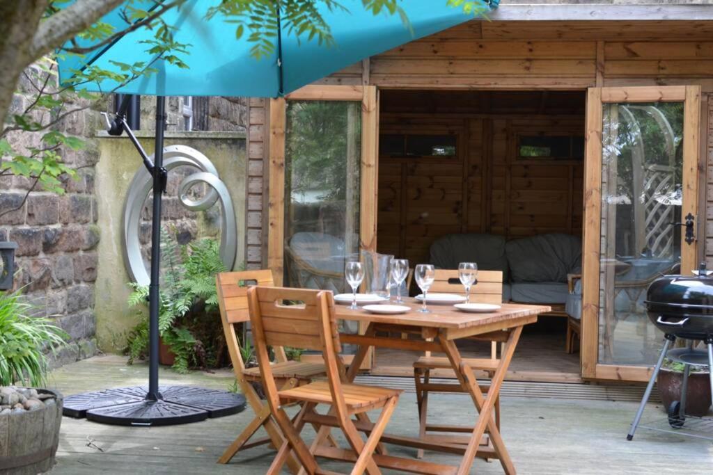 - une table en bois avec des chaises et un parasol sur la terrasse dans l'établissement Spacious Victorian Townhouse near HCC with off street parking, à Harrogate
