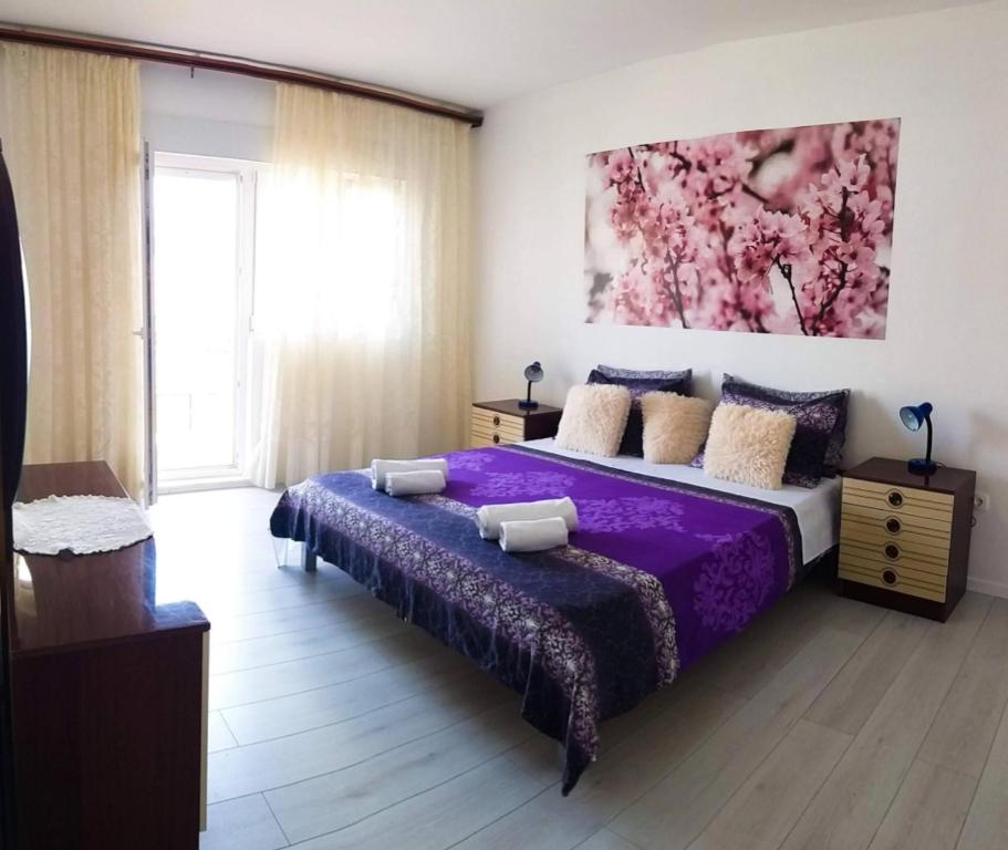 a bedroom with a purple bed and a painting on the wall at Apartmani Čagalj in Trogir