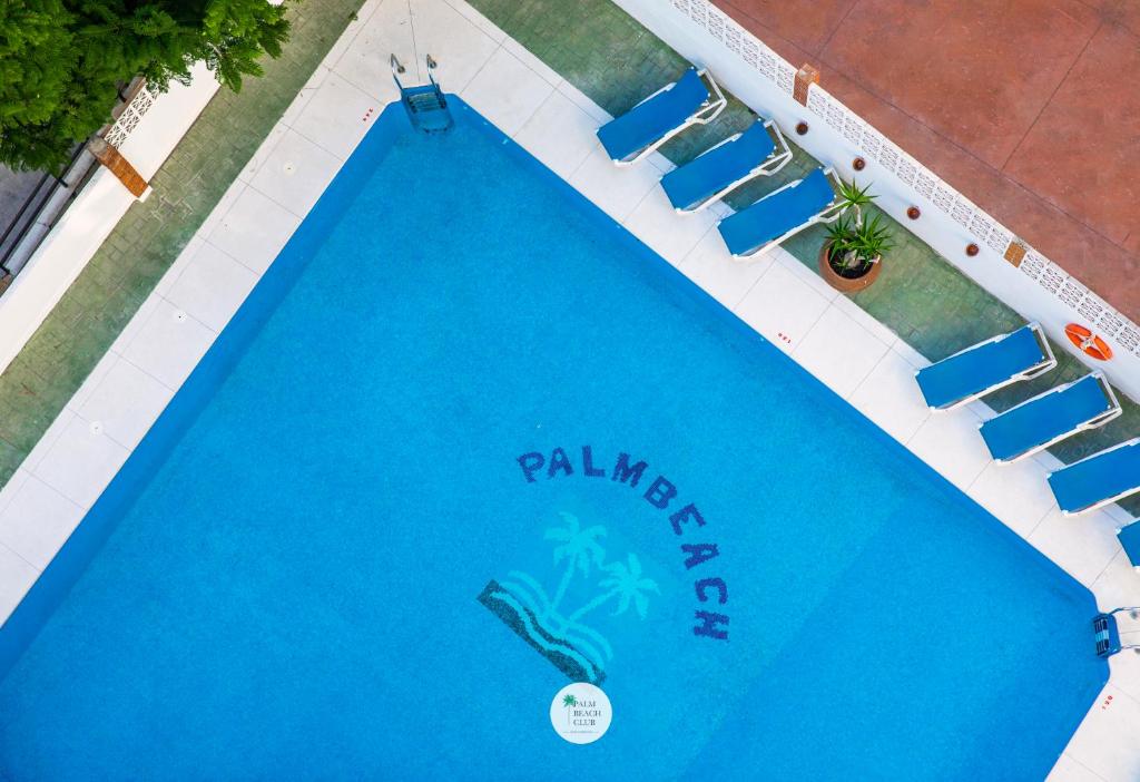 una vista aérea de una piscina con sillas azules en Apartamentos Palm Beach Club Carihuela, en Torremolinos