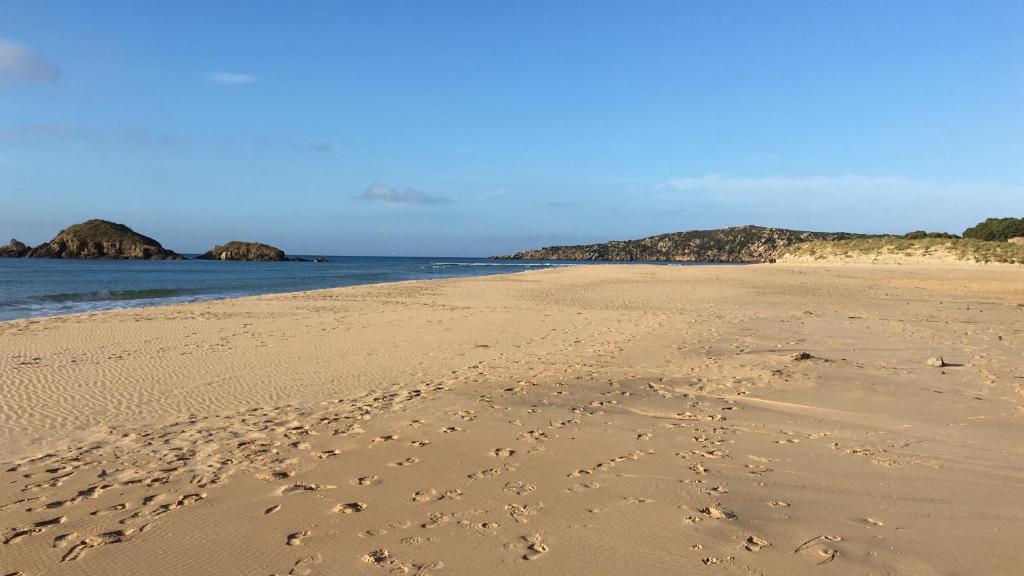 a beach with footprints in the sand and the ocean at Cottage Su Giudeu in Chia