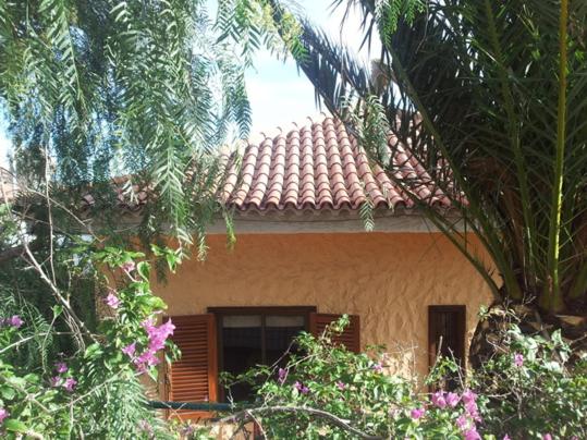 een huis met een betegeld dak en enkele bomen en bloemen bij CASA FAMILIA - RELAX in San Isidro