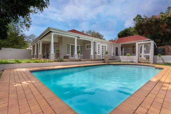 a large blue swimming pool in front of a house at Middelberg Manor in Pretoria