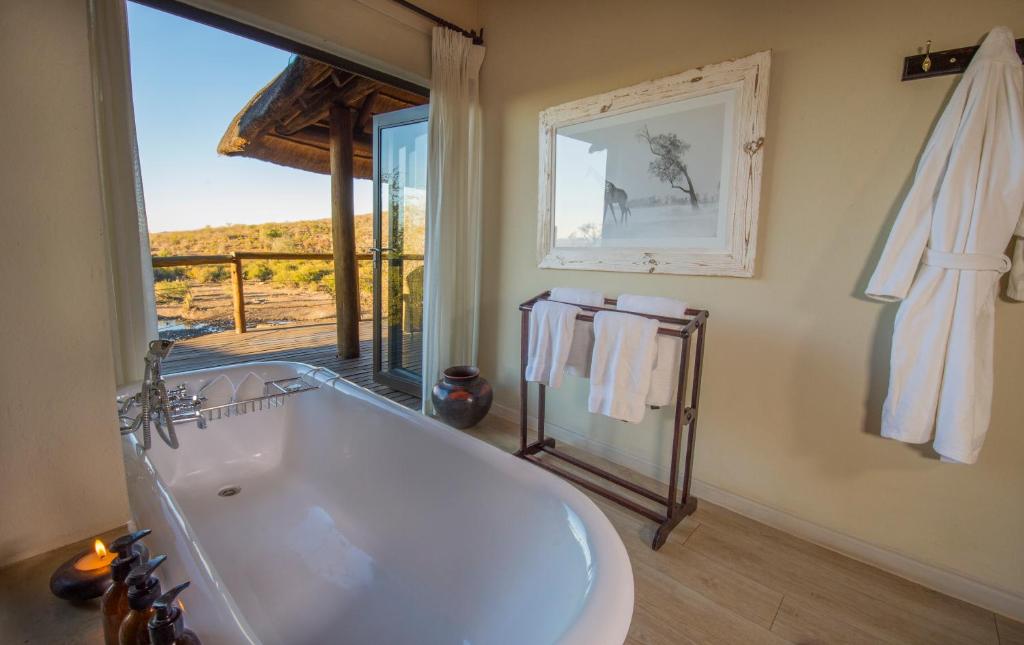 baño con bañera grande y ventana en Impodimo Game Lodge en Madikwe Game Reserve