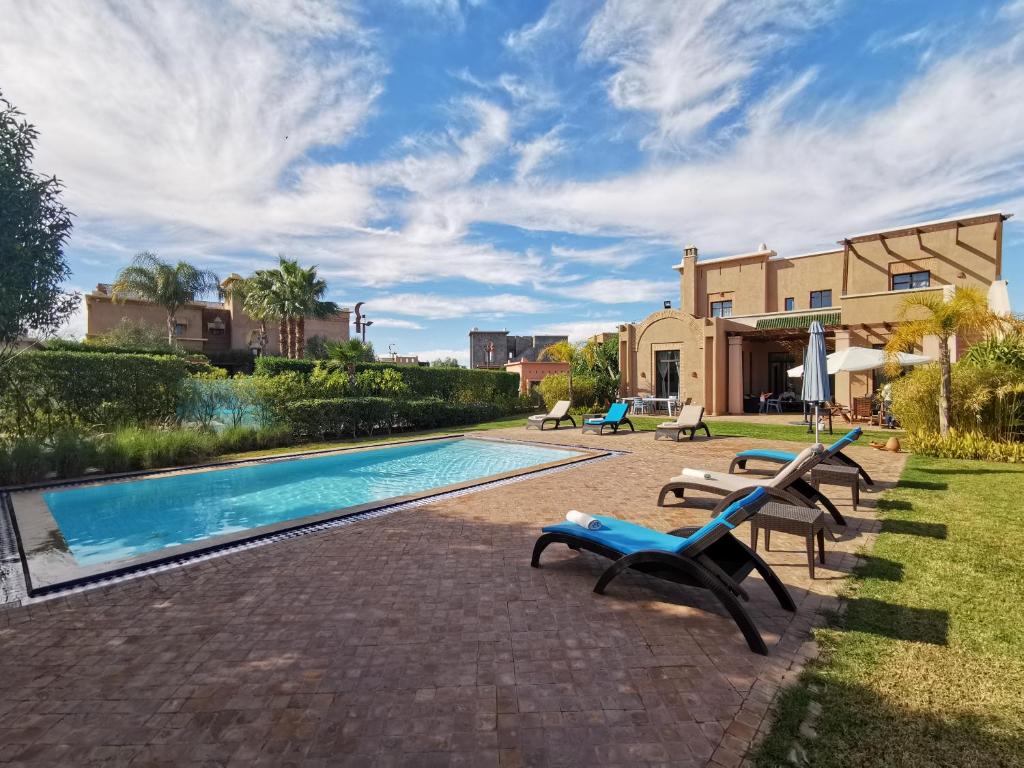 a swimming pool with lounge chairs and a house at Marrakech Pearl in Marrakech
