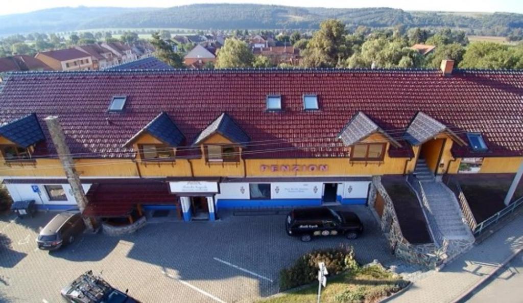 a building with a red roof with cars parked in a parking lot at Penzion U Holuba in Hradčovice