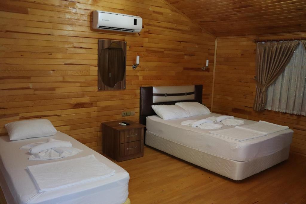 two beds in a room with wooden walls at Plaj Hotel in Cıralı