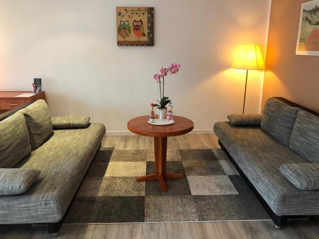 a living room with two couches and a table with flowers on it at Apartmenthaus Zeuthen in Zeuthen