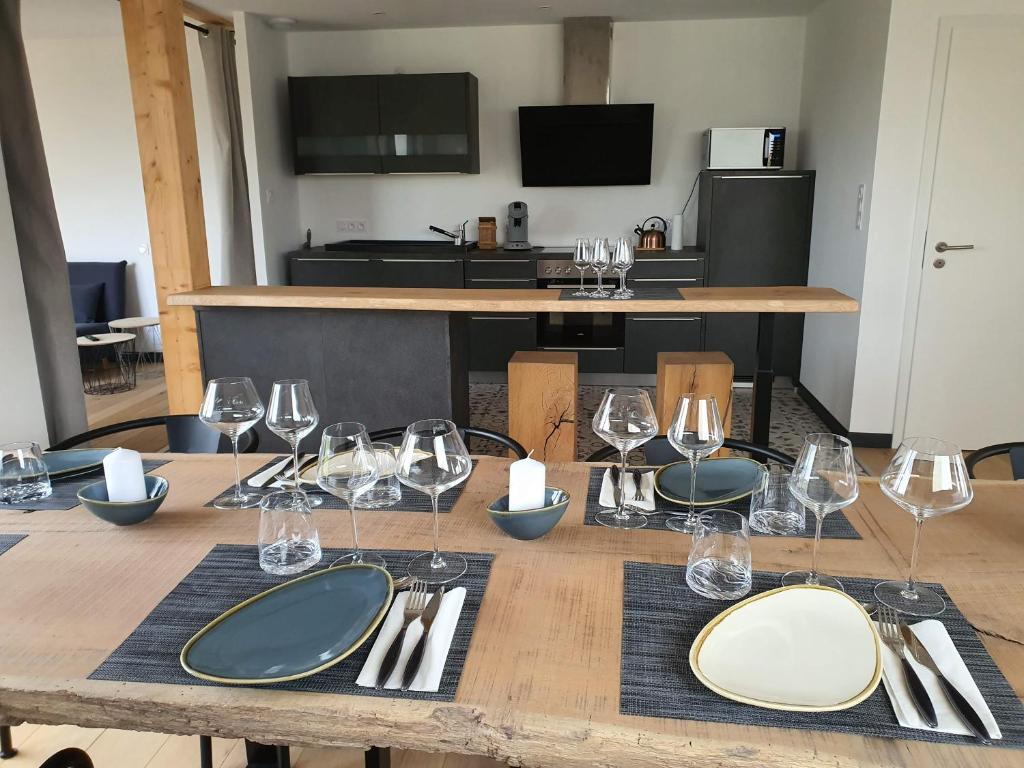 een houten tafel met wijnglazen en bestek erop bij Le Cottage de Vany in Vany