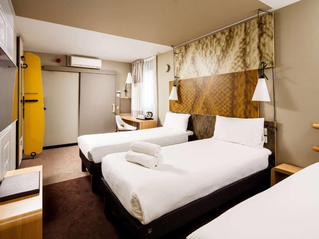 a hotel room with two beds with white sheets at ibis London City - Shoreditch in London