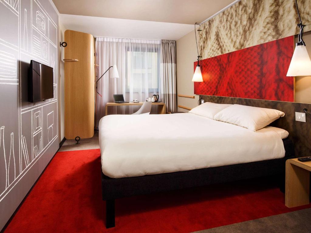 um quarto de hotel com uma cama grande e um tapete vermelho em ibis London City - Shoreditch em Londres