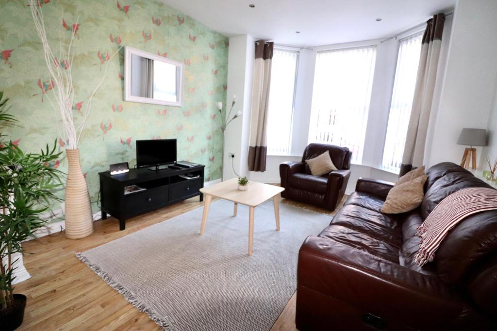 a living room with a leather couch and a table at Clifton Park in Belfast