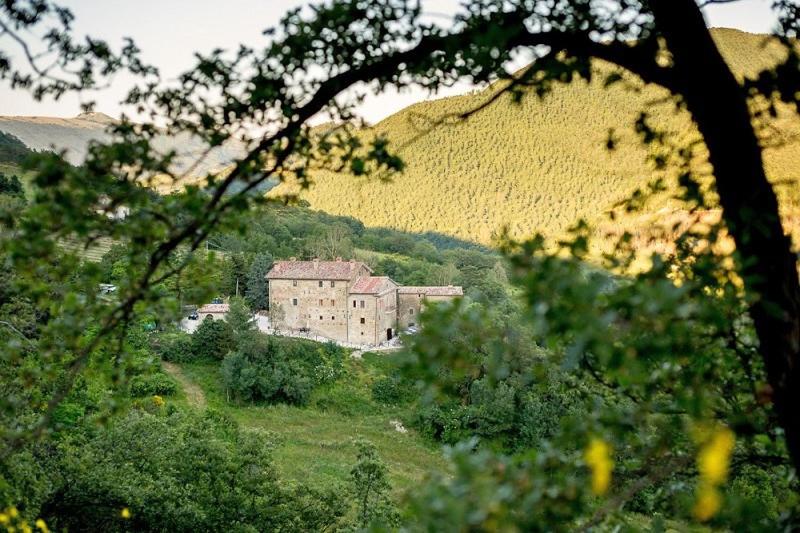 a building in the middle of a field with trees at Country House Villa La Farfalla in Pietralunga