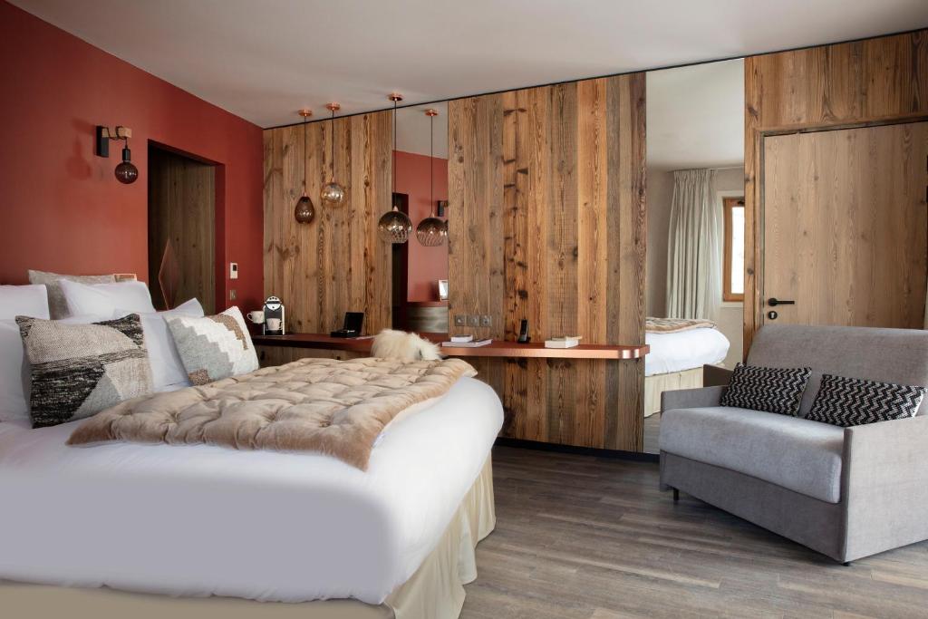 a bedroom with a large bed and a chair in it at Grandes Rousses Hotel & Spa in L'Alpe-d'Huez