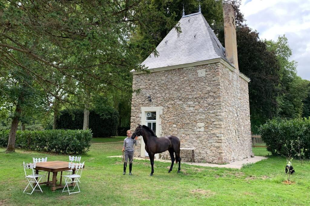 a man standing next to a horse in front of a building at Romantic anciens cottage in a beautiful park in La Fontaine-Saint-Martin