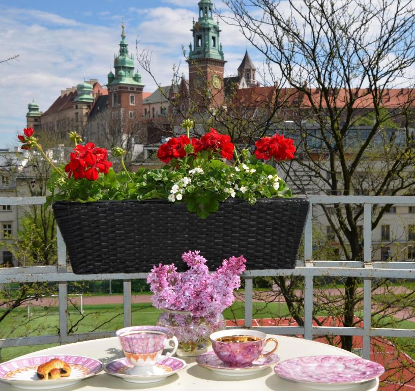 a table with plates and cups and flowers on a fence at Castle View Boutique Apartment in Krakow