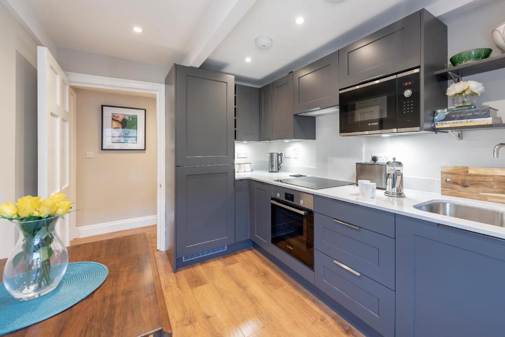 a kitchen with blue cabinets and a vase of flowers at Stunning & Central Milsom Street Apartment in Bath