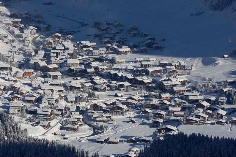 a village covered in snow with houses on a mountain at Fürmesli Appartements in Lech am Arlberg