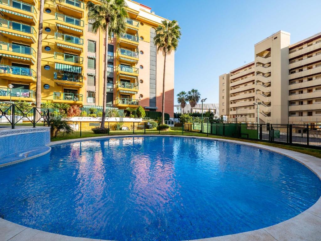 una gran piscina azul frente a algunos edificios en PALM BEACH APARTMENT - Torremolinos, en Torremolinos