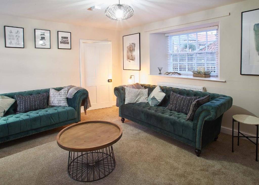 a living room with two green couches and a table at Host & Stay - Middle Farmhouse in Whitby