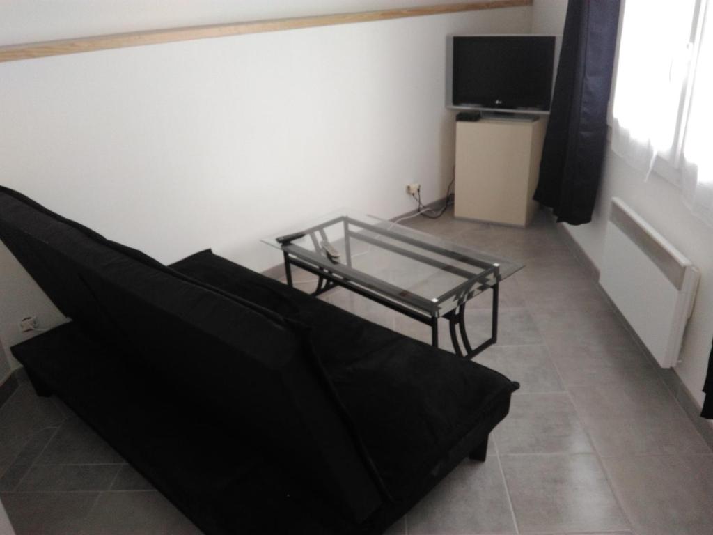uma sala de estar com um sofá preto e uma mesa em jolie appartement centre de Fismes em Fismes