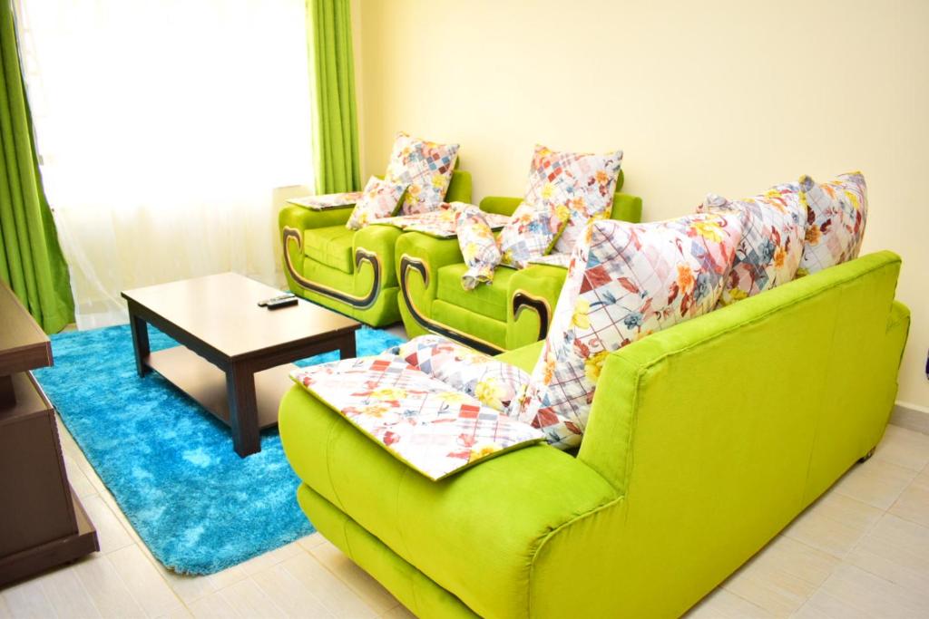 a living room with two green couches and a table at Great house BnB near jkia in Nairobi