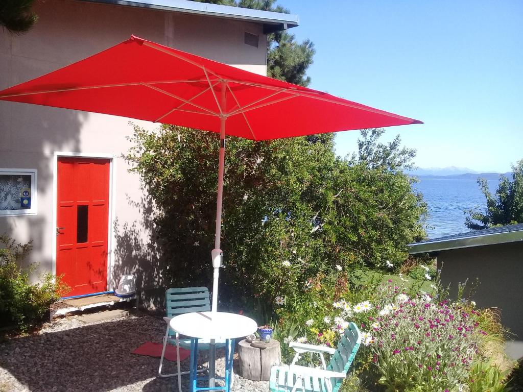 una sombrilla roja sobre una mesa y dos sillas en San Benito de Palermo en San Carlos de Bariloche