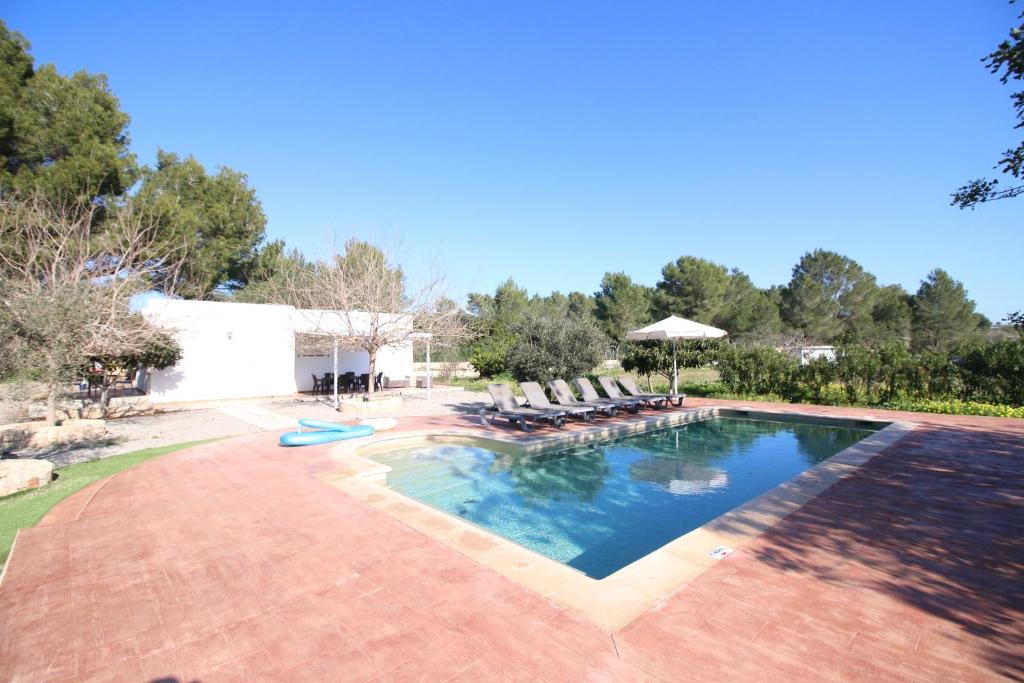 uma grande piscina com cadeiras e um guarda-sol em Villa Sa Barda em San Antonio