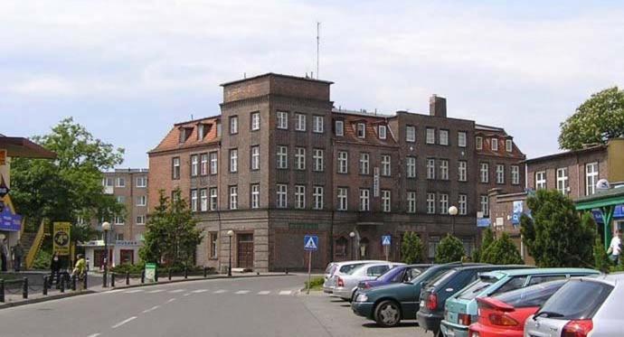 a large brick building with cars parked in a parking lot at Dom Turysty in Kostrzyn nad Odrą
