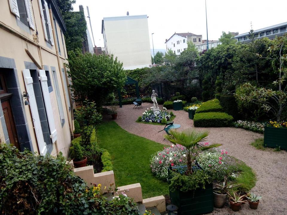 un jardin avec des plantes et des fleurs et un bâtiment dans l'établissement Propriété Charbaymond, à Clermont-Ferrand