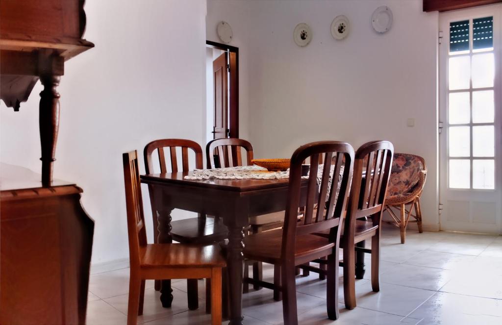 a dining room with a wooden table and chairs at Casa Cor-de-Rosa in Vila Nova de Milfontes