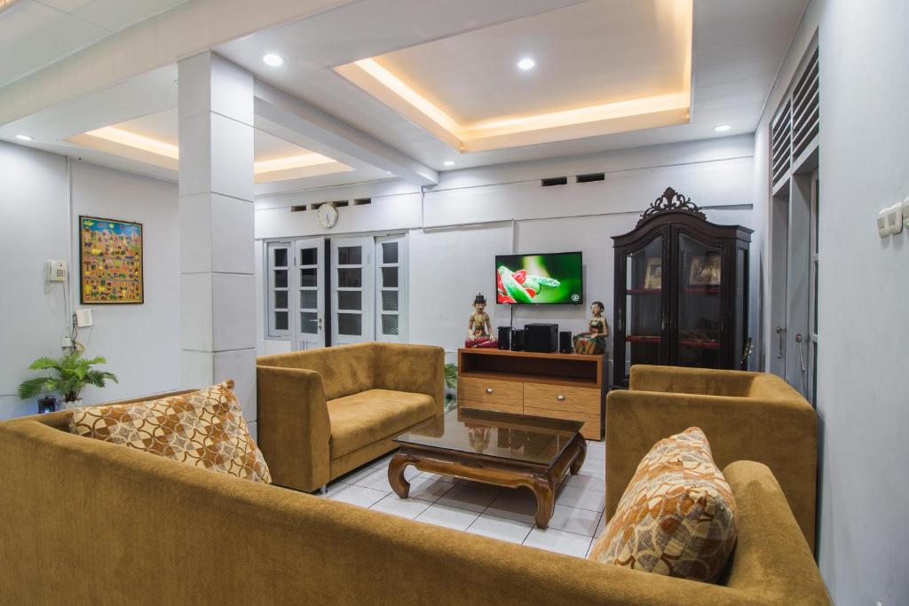 a living room with two couches and a tv at Ndalem Sarengat in Yogyakarta