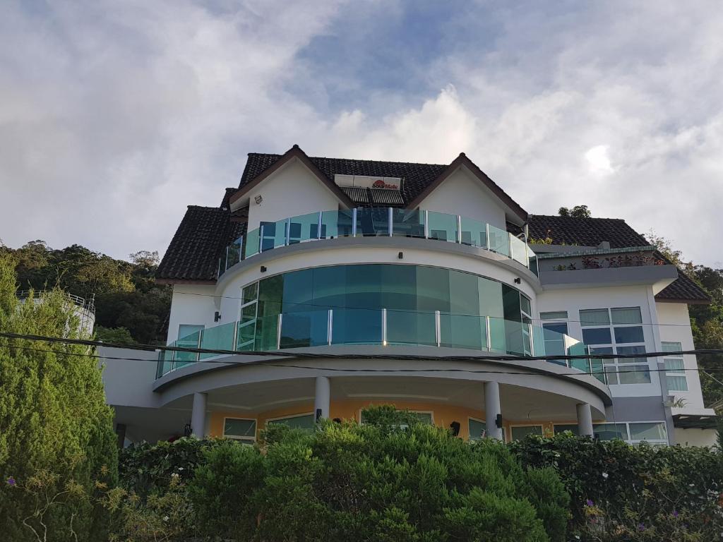 a white house with a balcony on top of it at Crystal Cameron Vacation Bungalow in Cameron Highlands