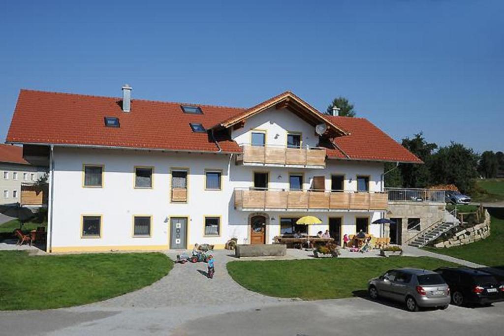 ein großes weißes Gebäude mit rotem Dach in der Unterkunft Exenbacher Hof in Arnbruck