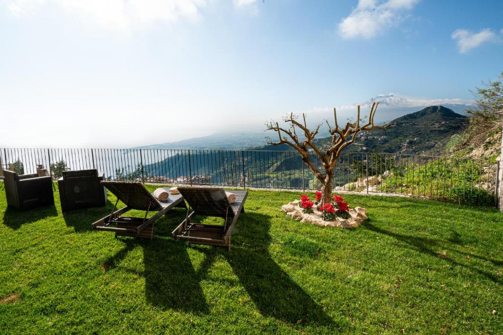 un paio di sedie sedute in un cortile con un albero di Taormina Rooms Panoramic Apartments a Taormina