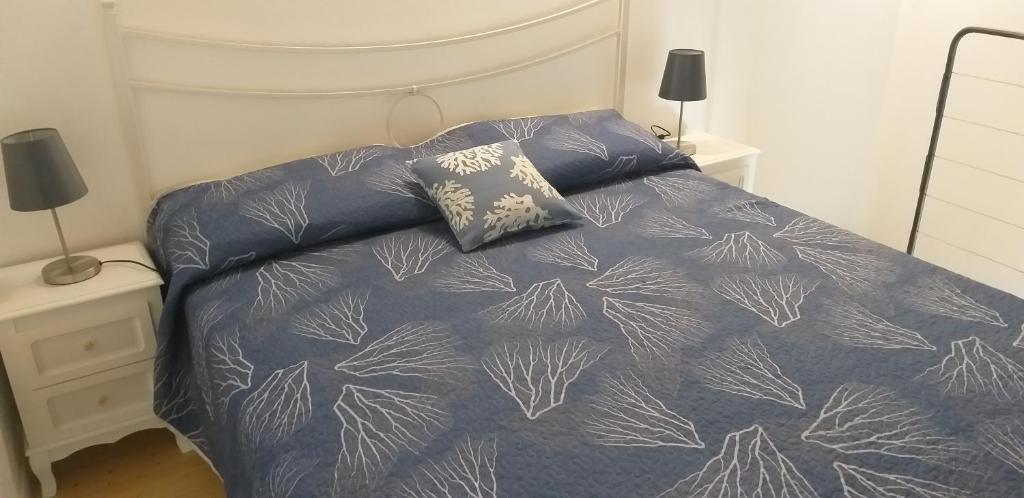 a bed with a blue comforter and two pillows at Residenza Solferino in Corniglia