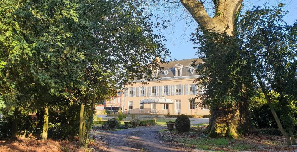 un gran edificio con un árbol delante en La Villa des Arts, en Savigné-lʼÉvêque