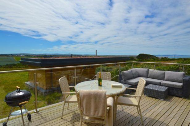 a deck with a couch and a table and chairs at Sea Gem in St. Agnes 