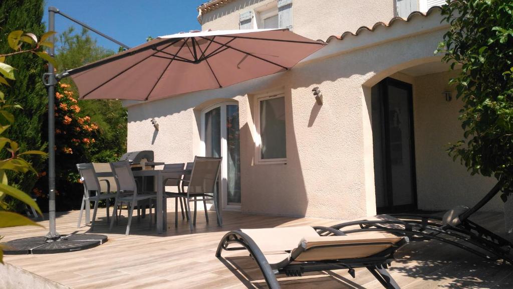 um pátio com uma mesa, cadeiras e um guarda-sol em Jolie individuelle wifi climatisée au cœur de la Provence à 40 km Verdon et de Ste Maxime em Lorgues