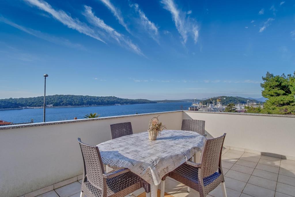 a table and chairs on a balcony with a view of the water at Apartments Žerjav in Mali Lošinj