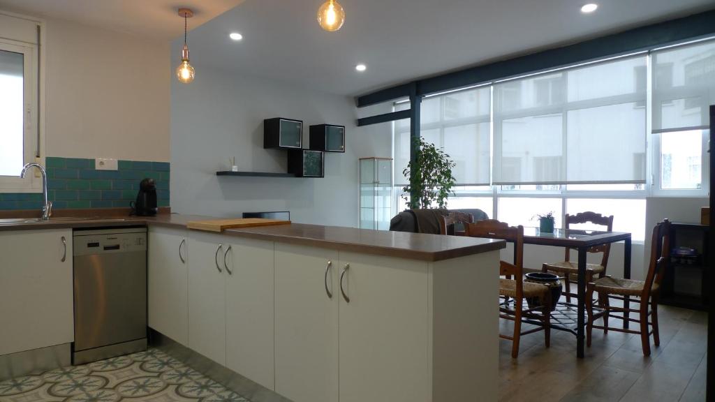 a kitchen with white cabinets and a table and a dining room at Living Triana House in Seville