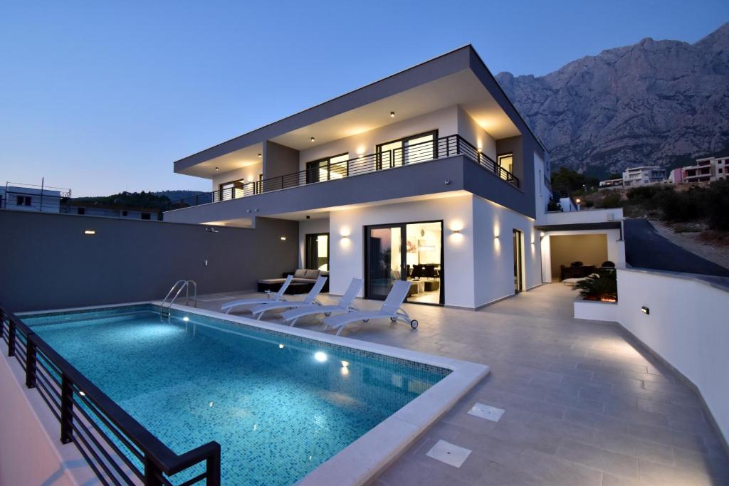 a house with a swimming pool in front of a house at Villa Alexandra - Makarska in Makarska