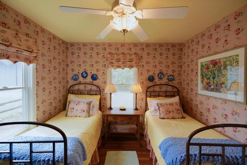 two beds in a room with pink wallpaper at Onion Creek Cottage in Austin