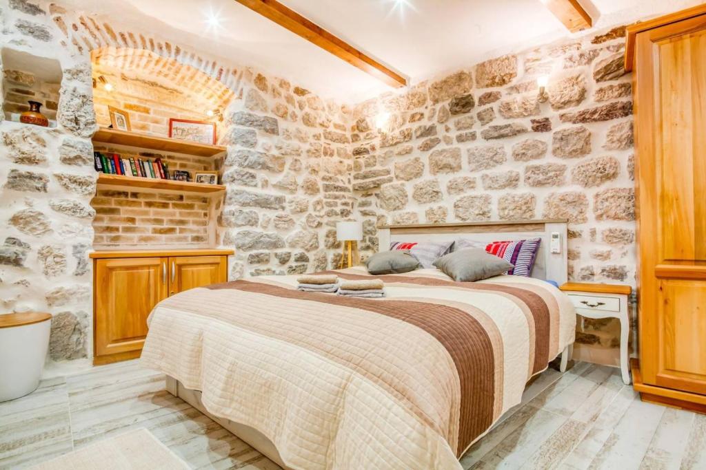 - une chambre avec un grand lit dans un mur en pierre dans l'établissement Kotor Bagus - Cozy Boutique Old Town Studio with Seaview Terrace, à Kotor