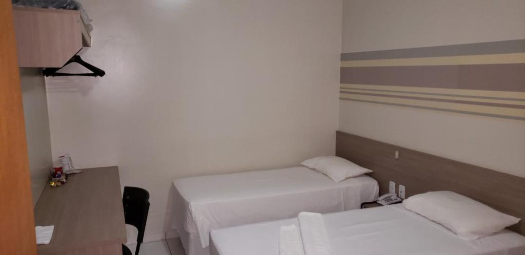 a room with two beds and a desk and a table at Hotel LG in Luis Eduardo Magalhaes