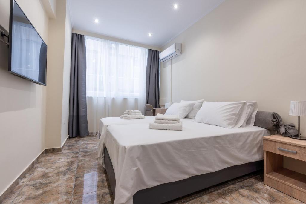 a bedroom with a large white bed and a television at Luxury Harbour Studios in Thessaloniki