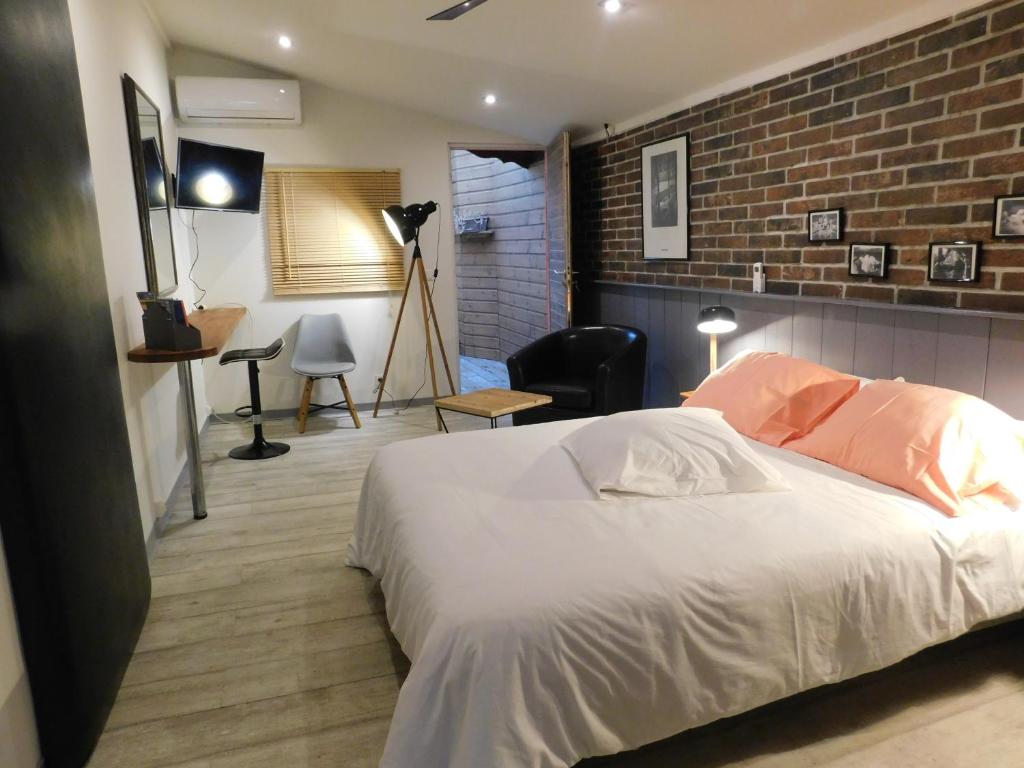 um quarto com uma cama branca e uma parede de tijolos em Studio Quisqualis em Sainte-Anne