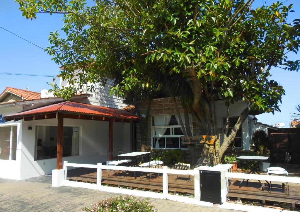 a house with a white fence and a tree at Hotel Los Ángeles in Mar del Plata