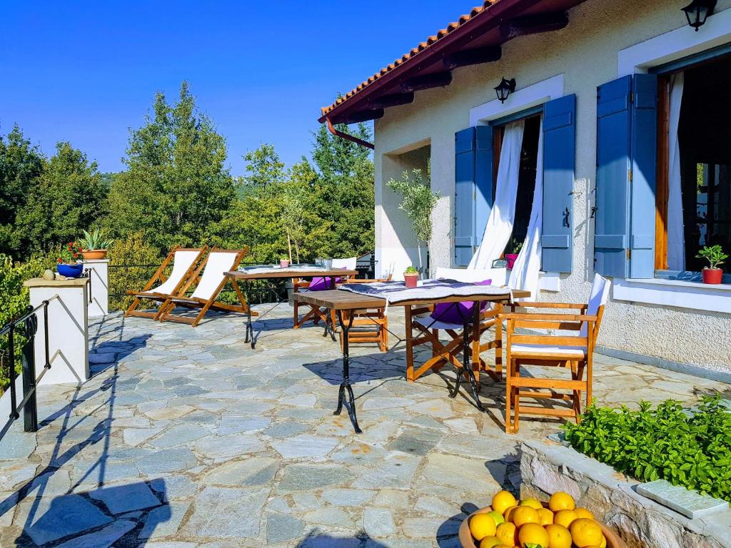 una casa con patio con mesas y sillas en Helicon Muses Friendly Mountain B&amp;B Guesthouse, en Evangelístria